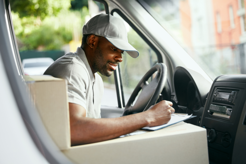 Courier.,Delivery,Man,Reading,Addresses,Sitting,In,Delivery,Van